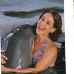 A woman in the water holding a dolphin.