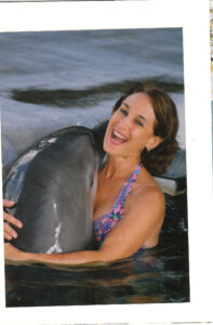 A woman in the water holding a dolphin.