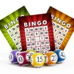 A group of bingo balls sitting next to three cards.