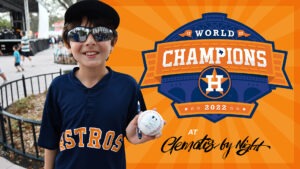 A boy holding a ball in front of an astros logo.