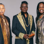 Three men in suits and scarves posing for a picture.